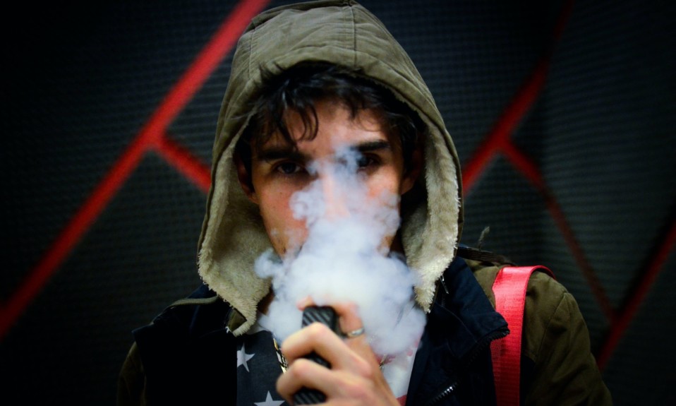 A teen uses an e-cigarette for vaping; lawsuits by school districts across the country accuse Juul of marketing to minors.